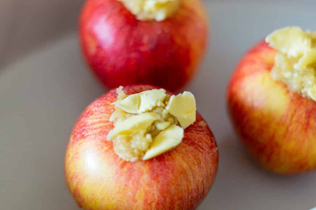 Fülle die Bratäpfel, gib Butter darüber und lege sie in eine Auflaufform