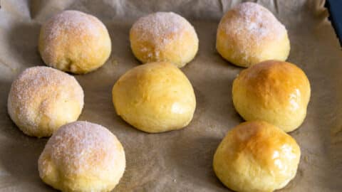 Berliner mit Butter bestreichen und mit Zucker bestreuen