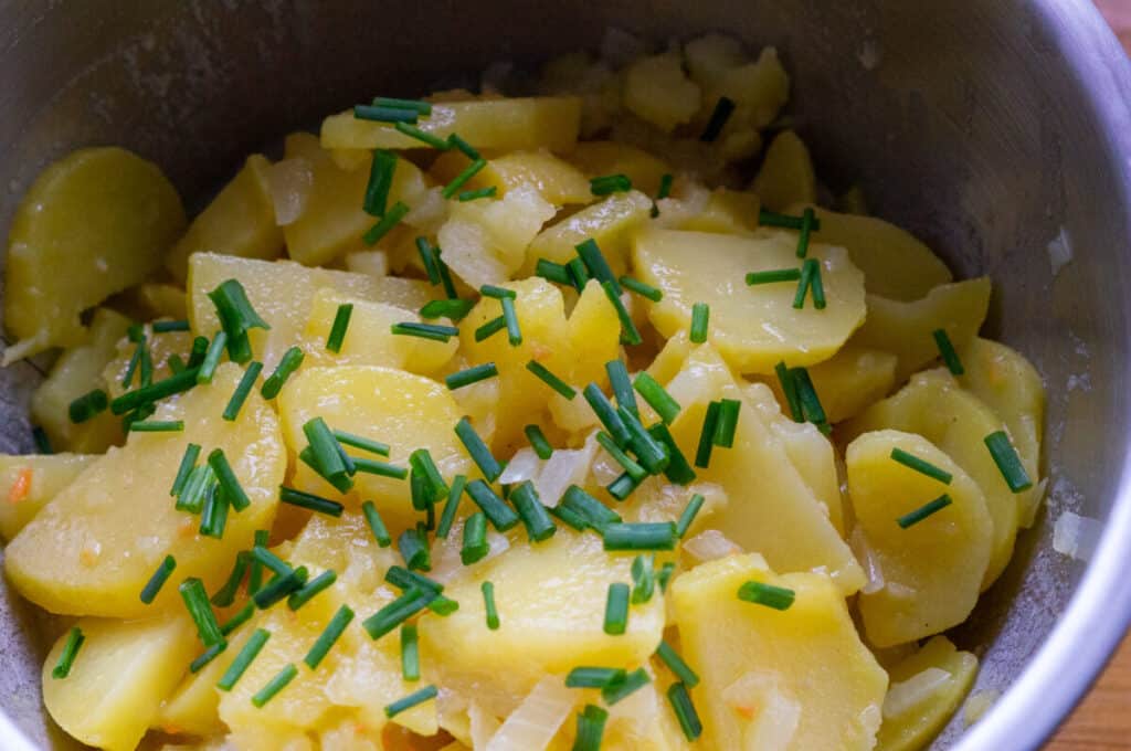 Kartoffelsalat mit Schnittlauch bestreuen