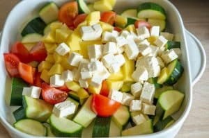 Gemüse und Feta für Zucchiniauflauf schneiden