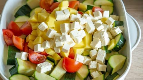 Gemüse und Feta für Zucchiniauflauf schneiden