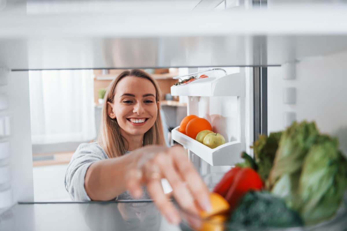 Frau nimmt Zutaten aus dem Kühlschrank