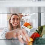 Frau nimmt Zutaten aus dem Kühlschrank