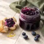 Heidelbeermarmelade im offenen Glas mit frischen Heidelbeeren