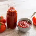 Hausgemachter Tomatenketchup in einer neutralen Flasche und Schale